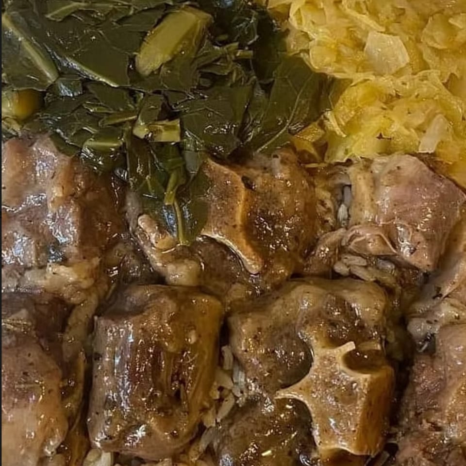 Close-up of Granny's Kitchen oxtails, collard greens, and cabbage, a classic soul food dish.