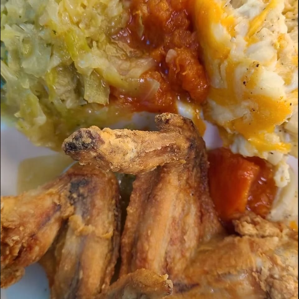 A close-up of Granny's Kitchen fried chicken, collard greens, macaroni and cheese, and candied yams.